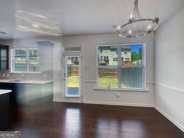 interior space featuring backsplash, hanging light fixtures, wood-type flooring, sink, and a notable chandelier