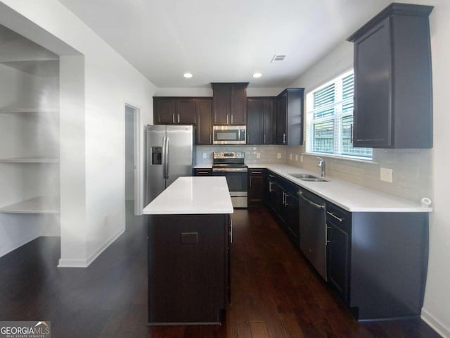 kitchen with a kitchen island, sink, tasteful backsplash, stainless steel appliances, and dark hardwood / wood-style floors