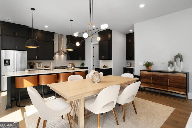 dining space featuring an inviting chandelier, sink, and light wood-type flooring