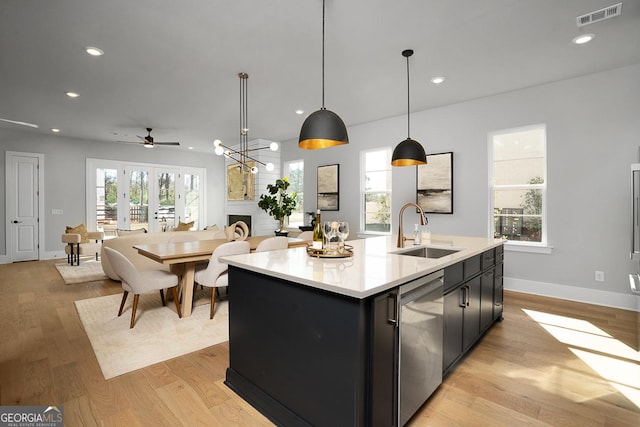 kitchen featuring sink, a kitchen island with sink, hanging light fixtures, a healthy amount of sunlight, and stainless steel dishwasher