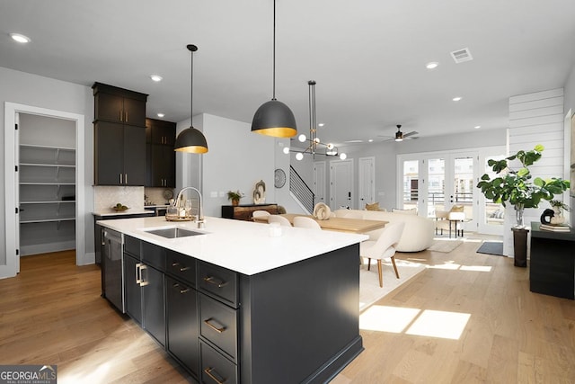 kitchen featuring an island with sink, sink, light hardwood / wood-style floors, and decorative light fixtures