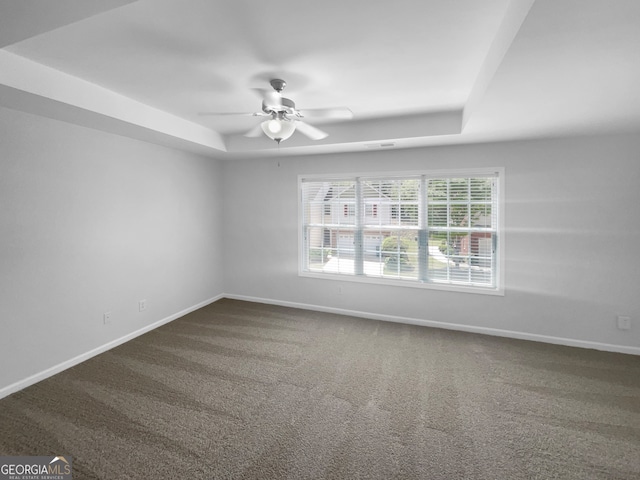 carpeted spare room featuring ceiling fan and a tray ceiling