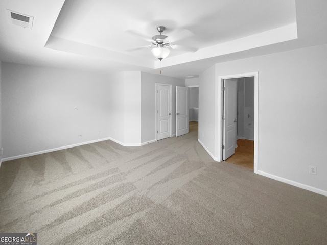 unfurnished bedroom featuring carpet, ceiling fan, and a tray ceiling