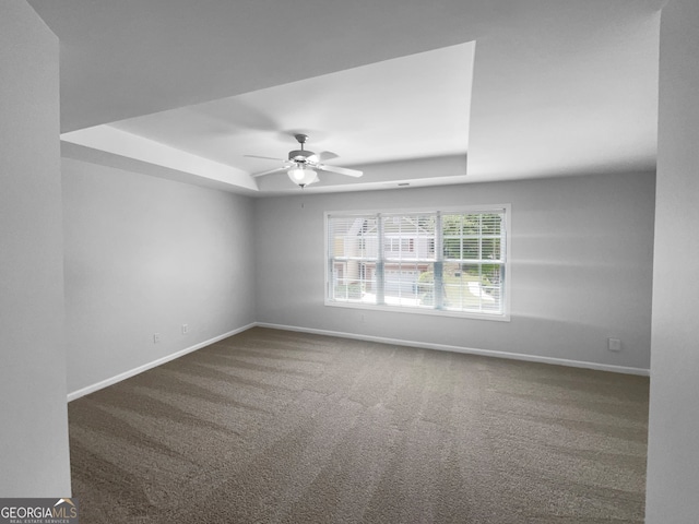 spare room featuring a raised ceiling, ceiling fan, and carpet flooring