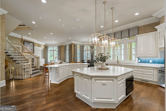 kitchen with a kitchen island, white cabinets, dark hardwood / wood-style flooring, ornamental molding, and pendant lighting