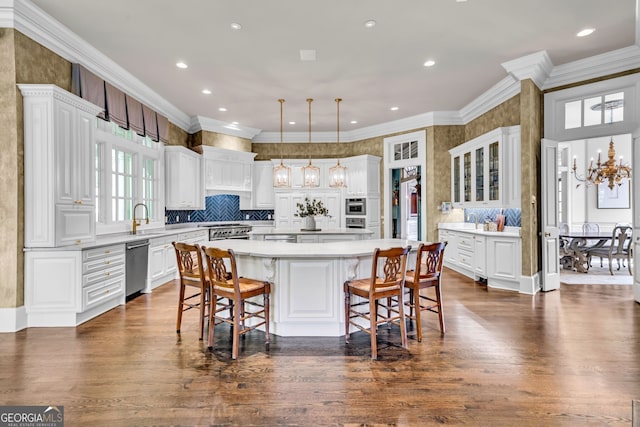 kitchen with white cabinetry, dark hardwood / wood-style floors, ornamental molding, appliances with stainless steel finishes, and a kitchen island