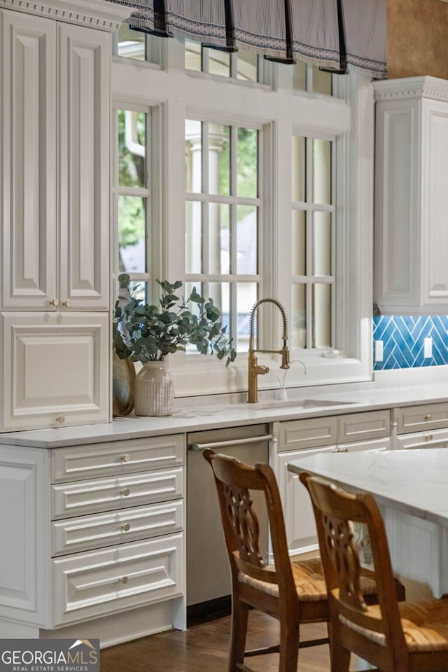 bar featuring white cabinets, dark wood-type flooring, backsplash, light stone counters, and dishwasher