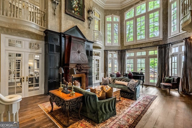 living room featuring wood-type flooring, a towering ceiling, and ornamental molding