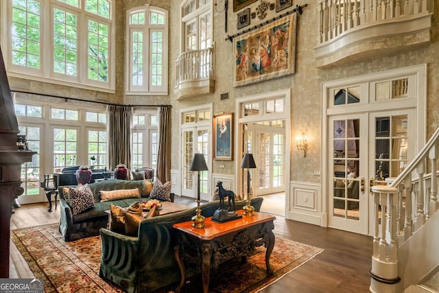 interior space with wood-type flooring, french doors, and a towering ceiling