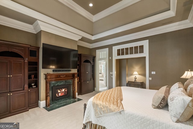 carpeted bedroom with crown molding, a tray ceiling, and a fireplace