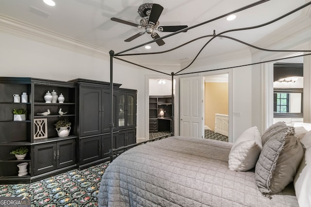 carpeted bedroom featuring crown molding, ceiling fan, and a walk in closet