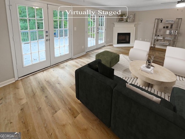 living room with crown molding, french doors, ceiling fan, and light wood-type flooring