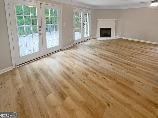 unfurnished living room featuring french doors, ceiling fan, crown molding, and light hardwood / wood-style flooring