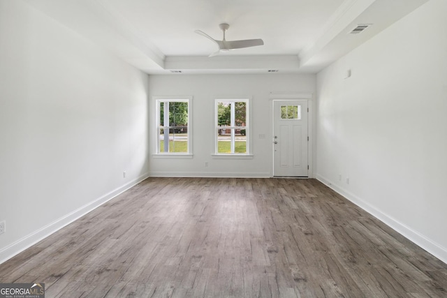 interior space featuring ceiling fan, wood-type flooring, and a tray ceiling