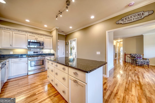 kitchen featuring light hardwood / wood-style flooring, ornamental molding, stainless steel appliances, a kitchen island, and dark stone counters