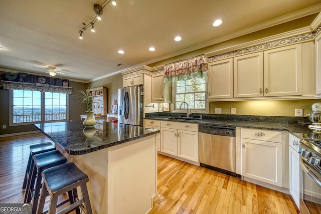 kitchen with ceiling fan, stainless steel appliances, light hardwood / wood-style floors, sink, and a center island