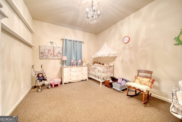 bedroom featuring an inviting chandelier, a crib, and carpet flooring