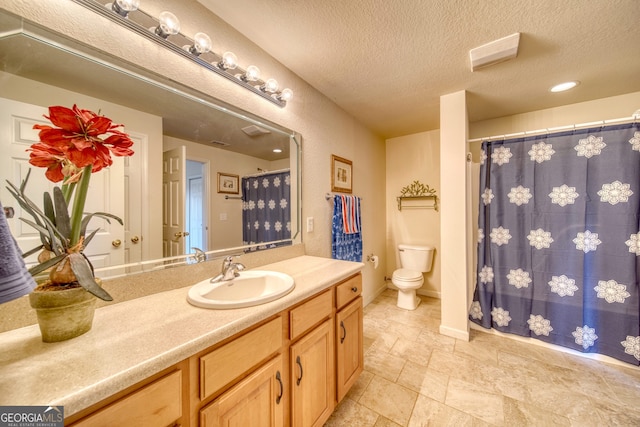 bathroom with a textured ceiling, vanity with extensive cabinet space, tile floors, and toilet