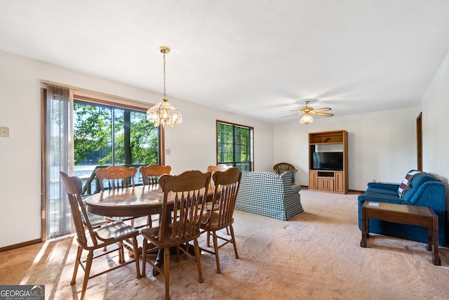 dining area with ceiling fan with notable chandelier and carpet