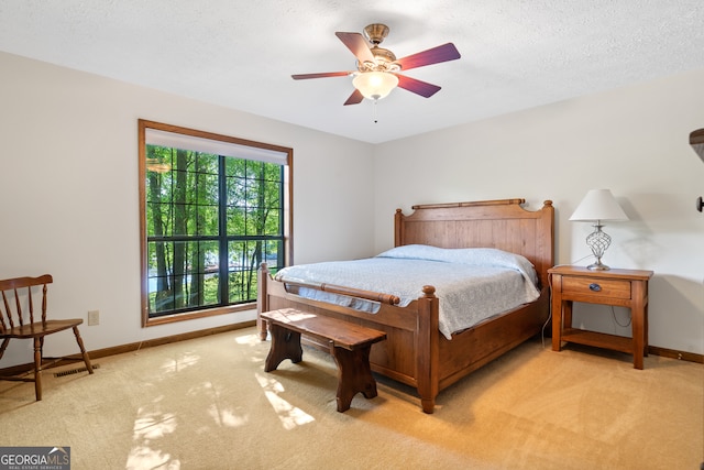 bedroom with ceiling fan, carpet, and a textured ceiling