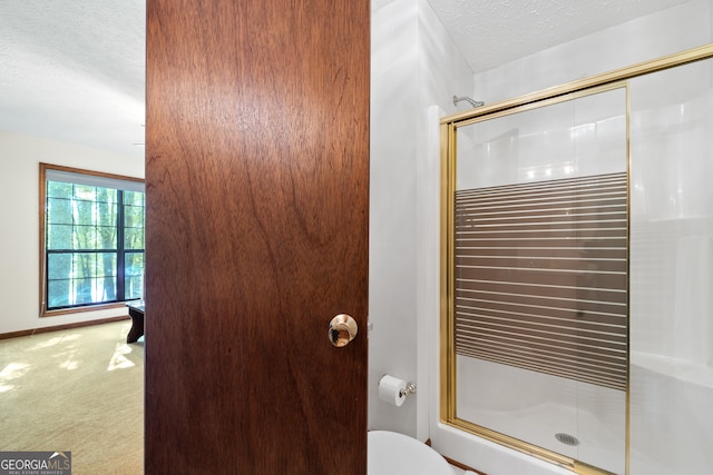 bathroom with toilet, a shower with shower door, and a textured ceiling