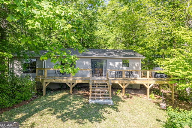 rear view of house with a wooden deck and a yard