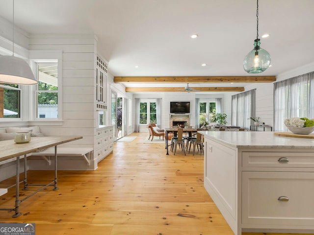 kitchen featuring wall chimney exhaust hood, stainless steel appliances, white cabinetry, light hardwood / wood-style floors, and a kitchen island