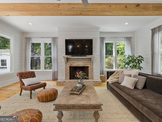 dining room featuring beamed ceiling, wood walls, a wealth of natural light, and light hardwood / wood-style flooring