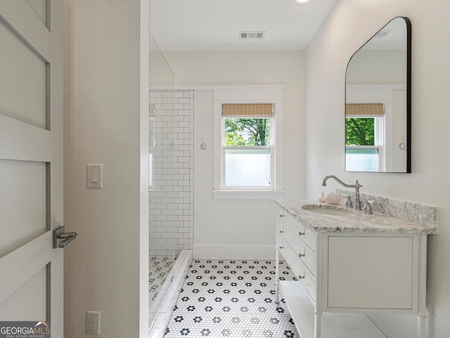 bathroom featuring a tile shower, vanity, and tile patterned floors