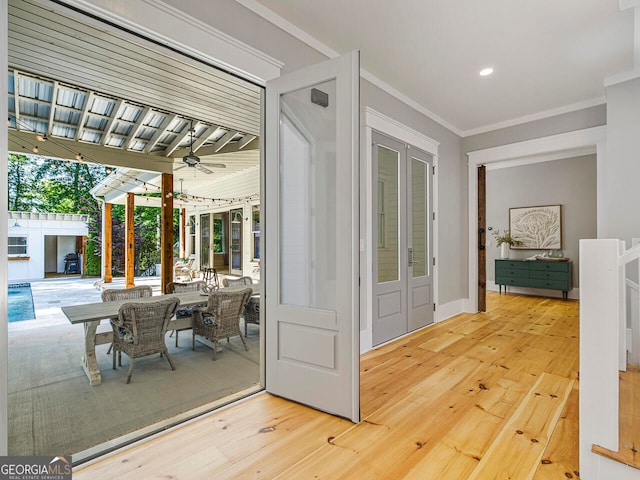 entrance foyer with a notable chandelier, a barn door, crown molding, and light hardwood / wood-style flooring