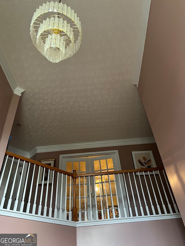 staircase featuring ornamental molding, a textured ceiling, and a chandelier