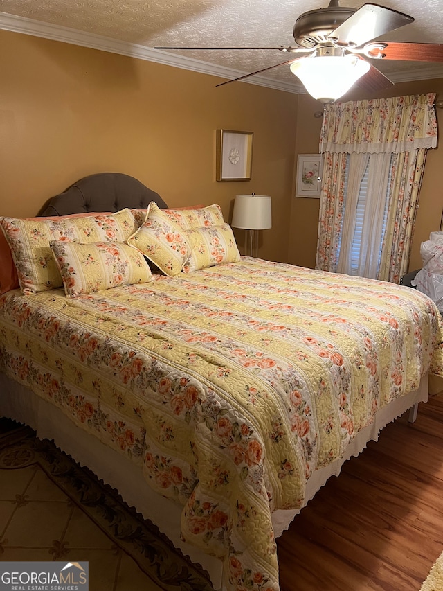 bedroom featuring a textured ceiling, ceiling fan, wood-type flooring, and ornamental molding