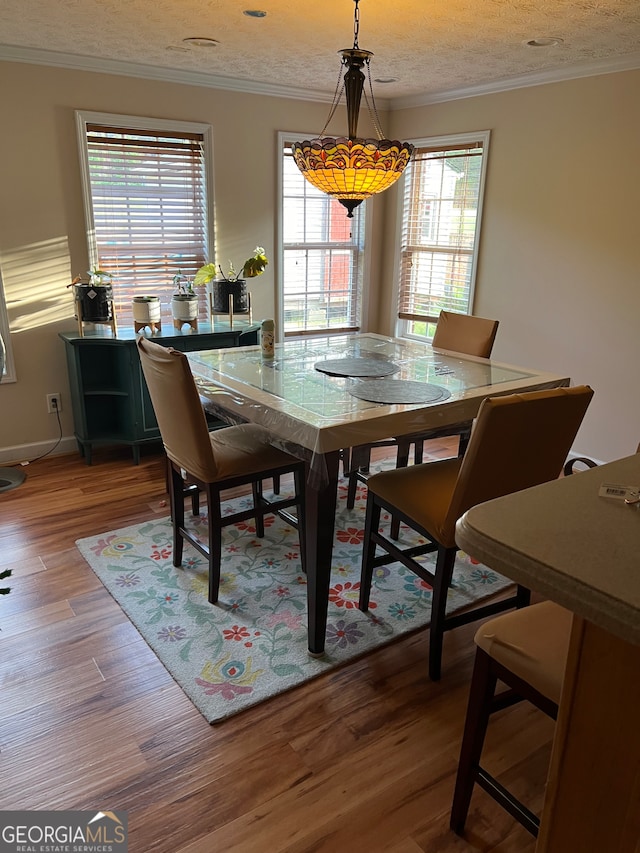 dining space featuring a textured ceiling, hardwood / wood-style floors, and ornamental molding