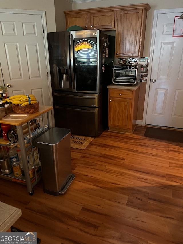 kitchen featuring stainless steel refrigerator with ice dispenser, decorative backsplash, and dark wood-type flooring