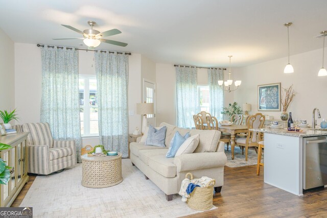 living room with ceiling fan with notable chandelier, wood-type flooring, and sink