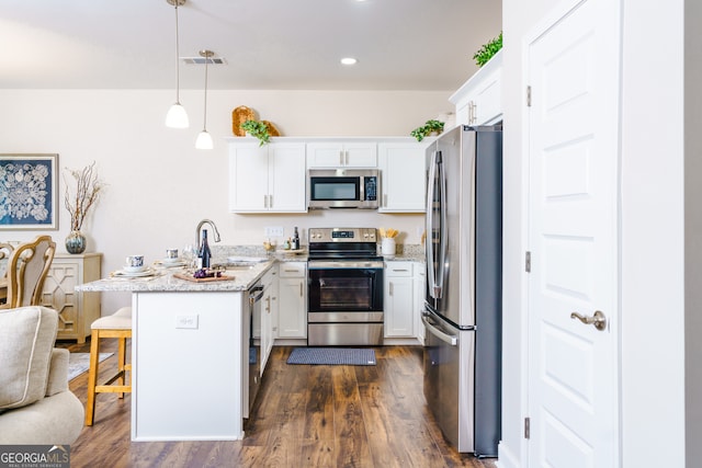 kitchen with white cabinetry, a breakfast bar area, dark wood-type flooring, stainless steel appliances, and decorative light fixtures