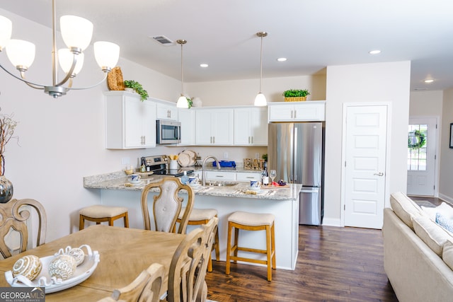 dining area with dark wood-type flooring, a notable chandelier, and sink