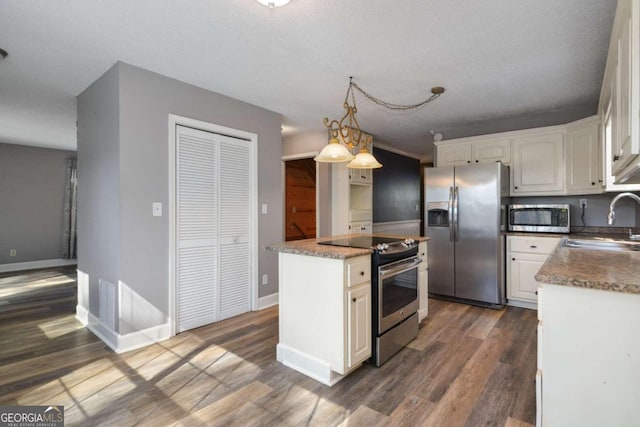 kitchen featuring appliances with stainless steel finishes, white cabinetry, a kitchen island, and dark wood-type flooring