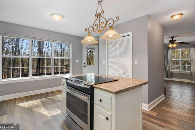 kitchen with decorative light fixtures, stainless steel electric range oven, dark wood-type flooring, white cabinets, and a center island