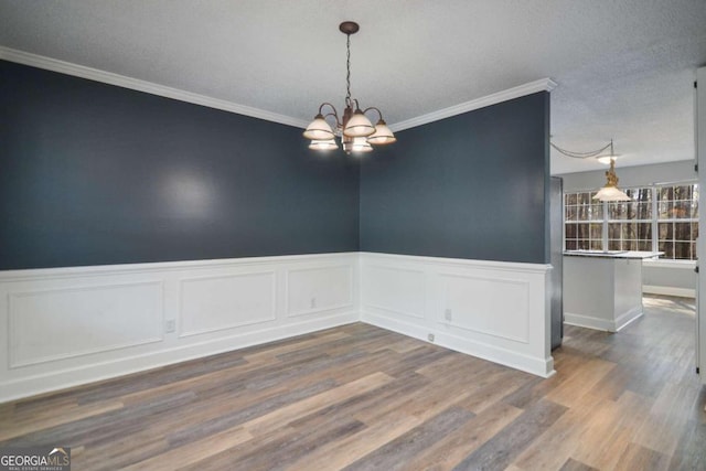 unfurnished room featuring ornamental molding, a textured ceiling, a chandelier, and dark wood-type flooring