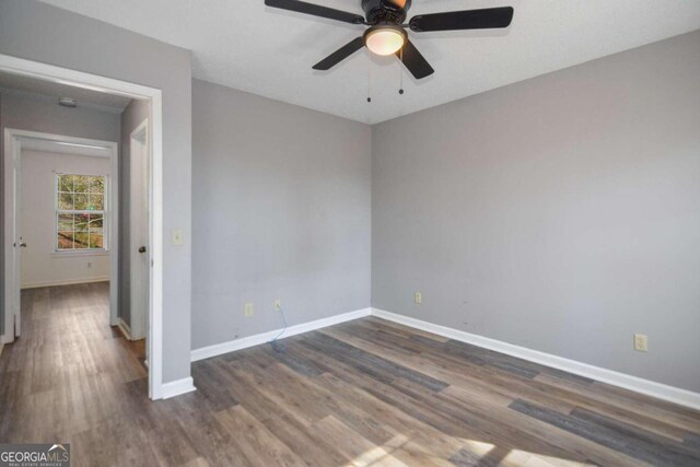 empty room featuring dark wood-type flooring and ceiling fan