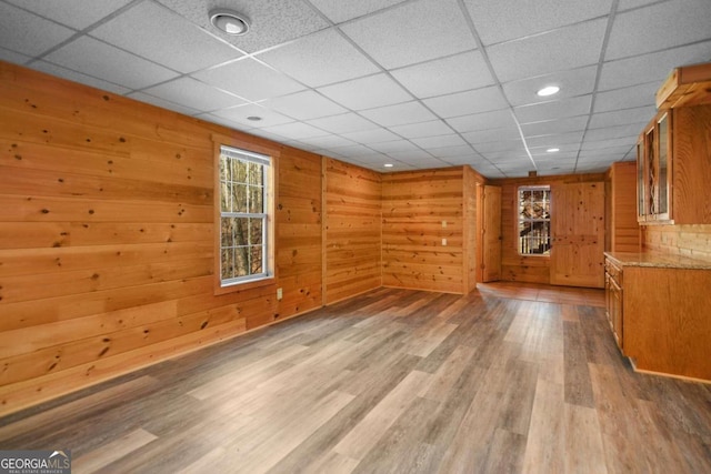 spare room with wood-type flooring, a paneled ceiling, and wood walls