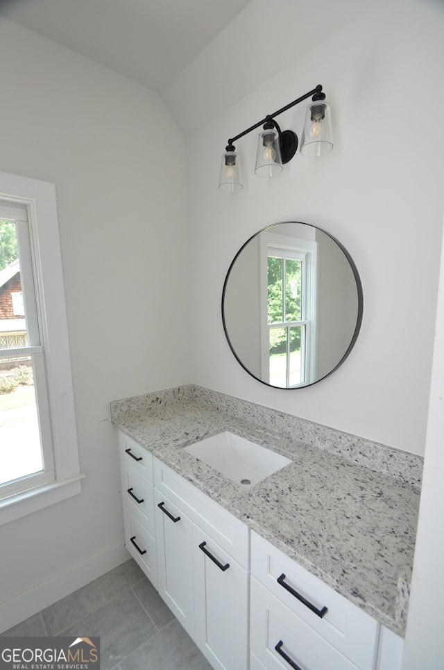 bathroom with tile patterned floors, vanity, and a healthy amount of sunlight