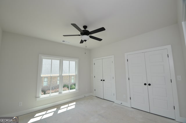 unfurnished bedroom with multiple closets and ceiling fan