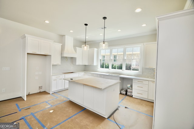 kitchen featuring white cabinetry, tasteful backsplash, a kitchen island, and custom exhaust hood