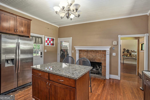 kitchen featuring light stone counters, a notable chandelier, stainless steel fridge with ice dispenser, dark hardwood / wood-style floors, and a kitchen island