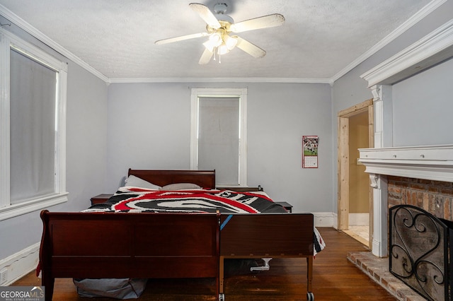 bedroom with a fireplace, dark hardwood / wood-style floors, ceiling fan, and crown molding