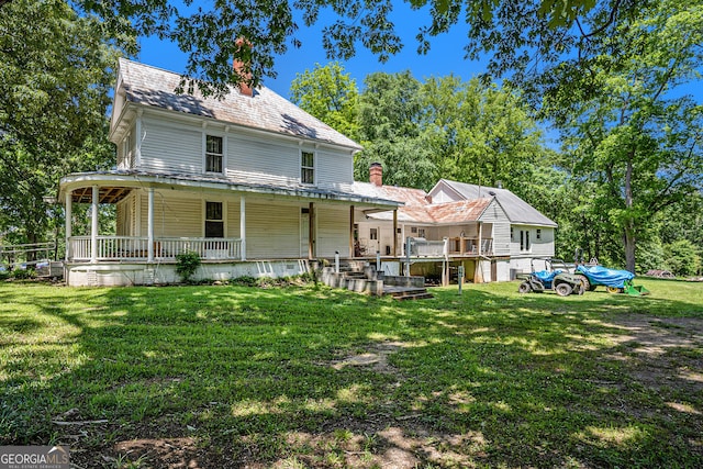 rear view of house featuring a lawn and covered porch