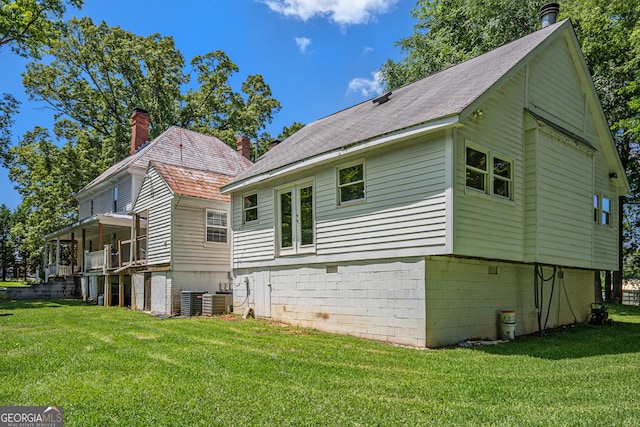 rear view of property with a yard and central air condition unit