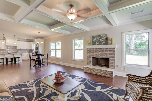 living room with beam ceiling, dark hardwood / wood-style flooring, a brick fireplace, and coffered ceiling